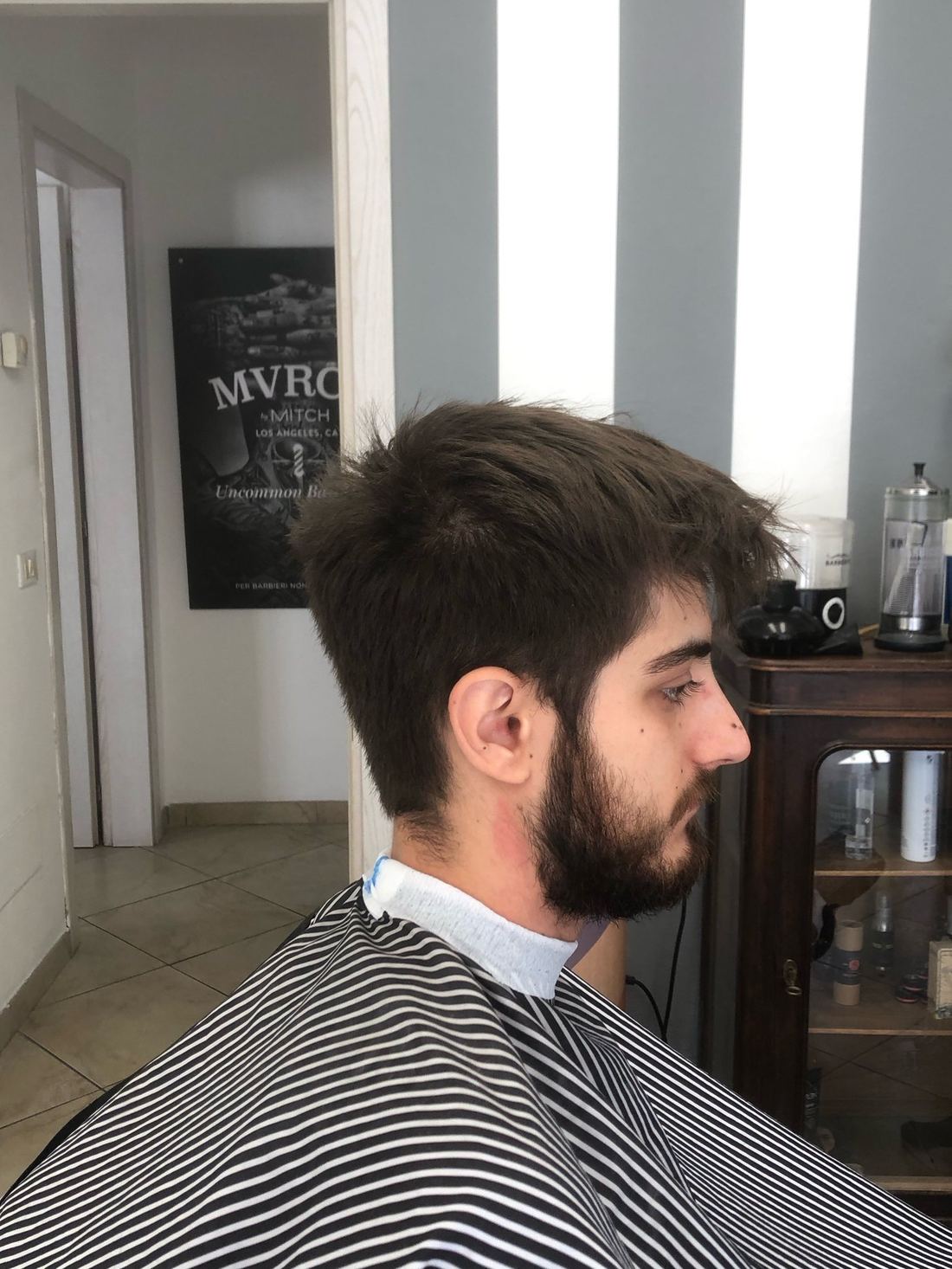 Taglio medio lungo con barba, visto di profilo, con la mantellina a righe